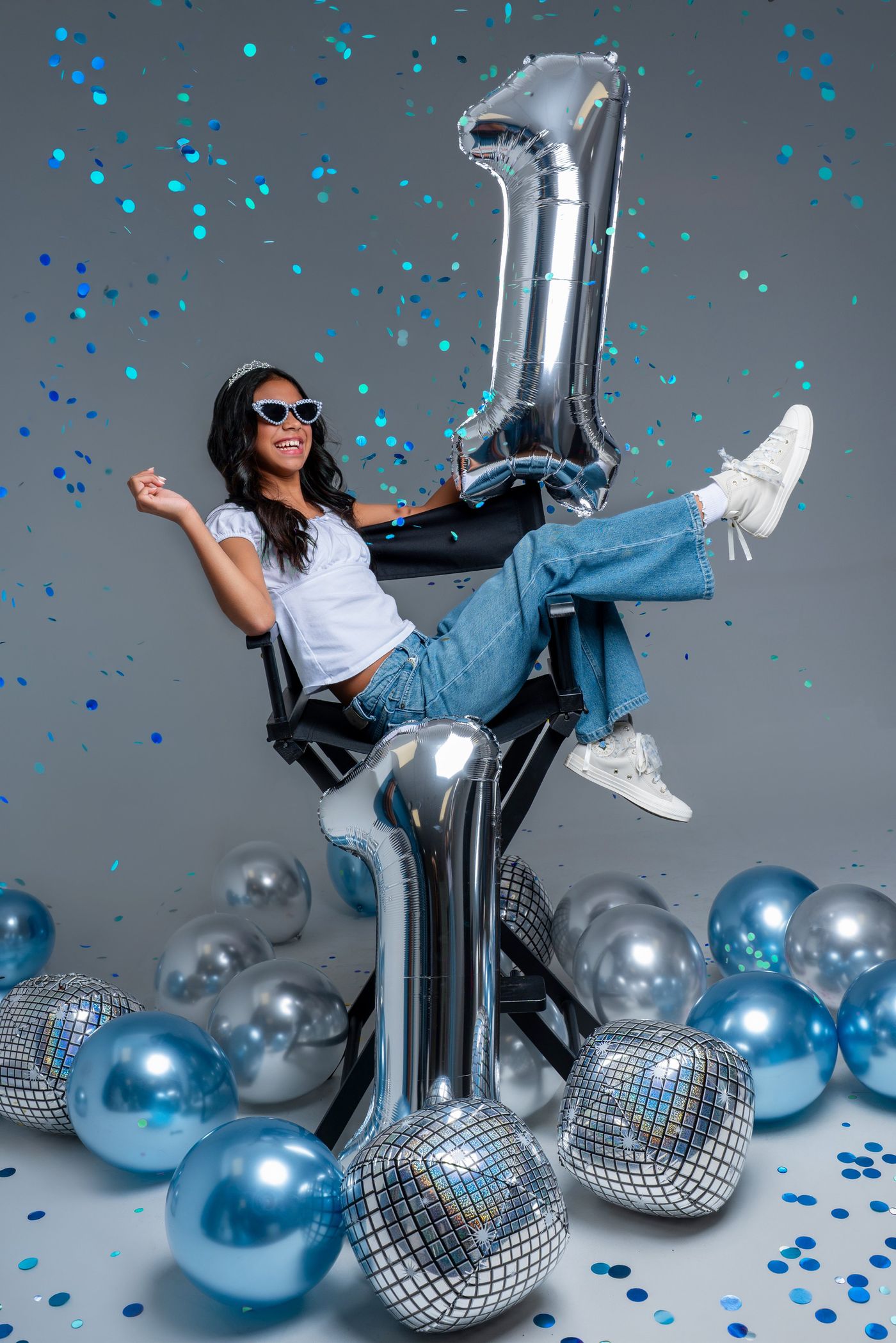 Girl celebrating with silver number balloons and confetti