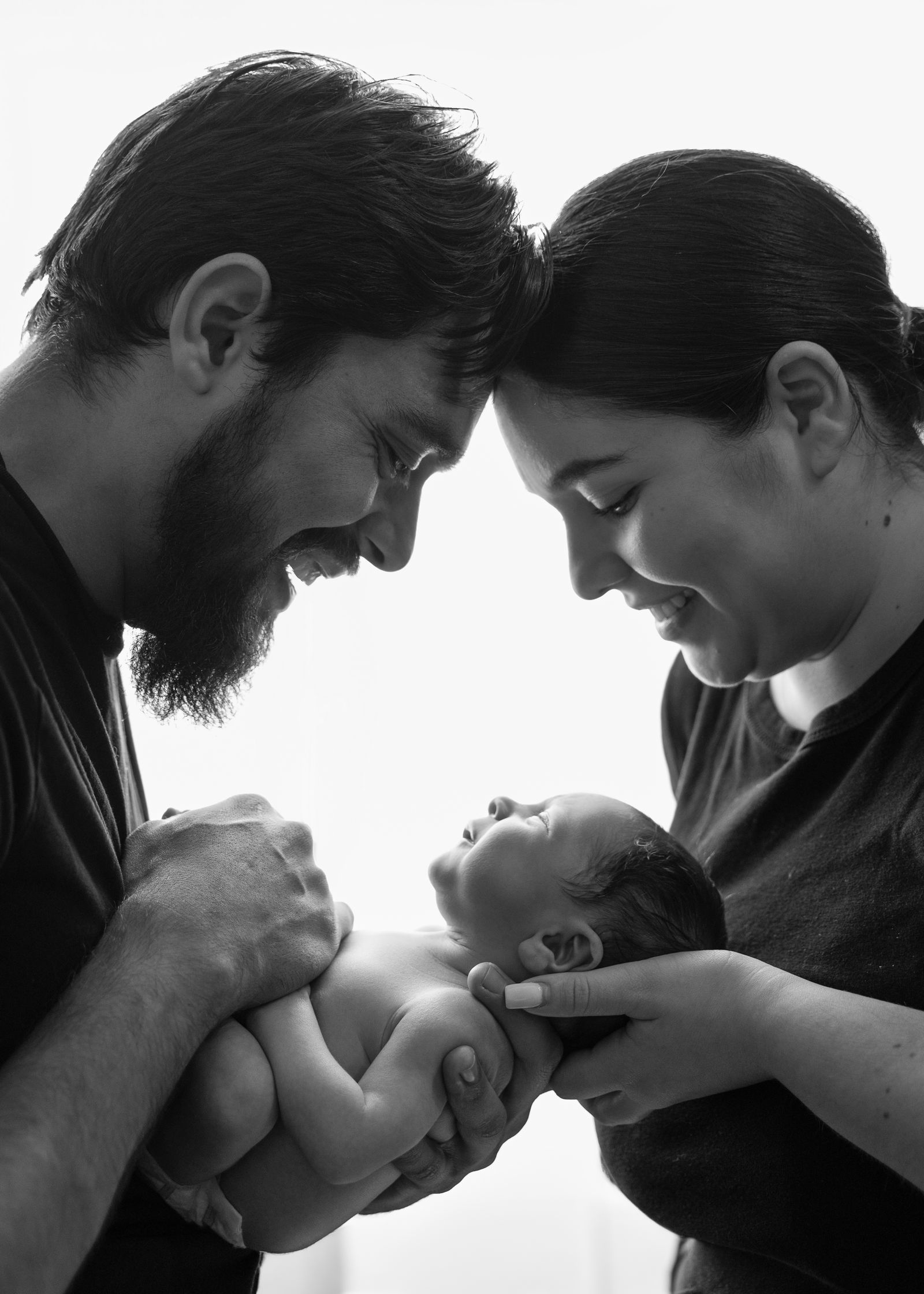 Black-and-white portrait of parents cradling their newborn
