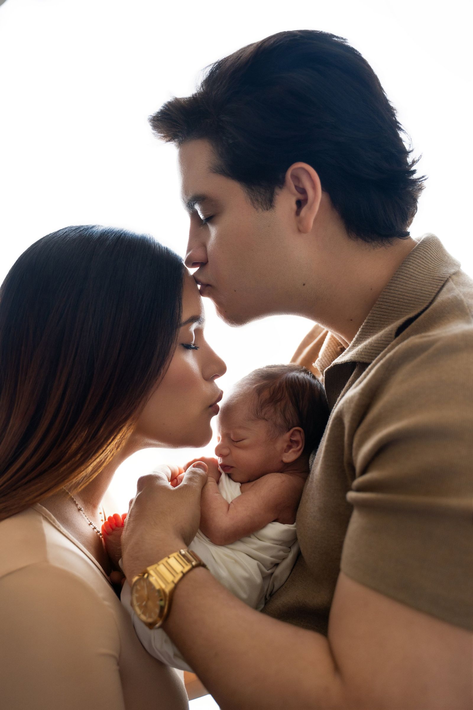 Parents holding a sleeping newborn, forehead to forehead