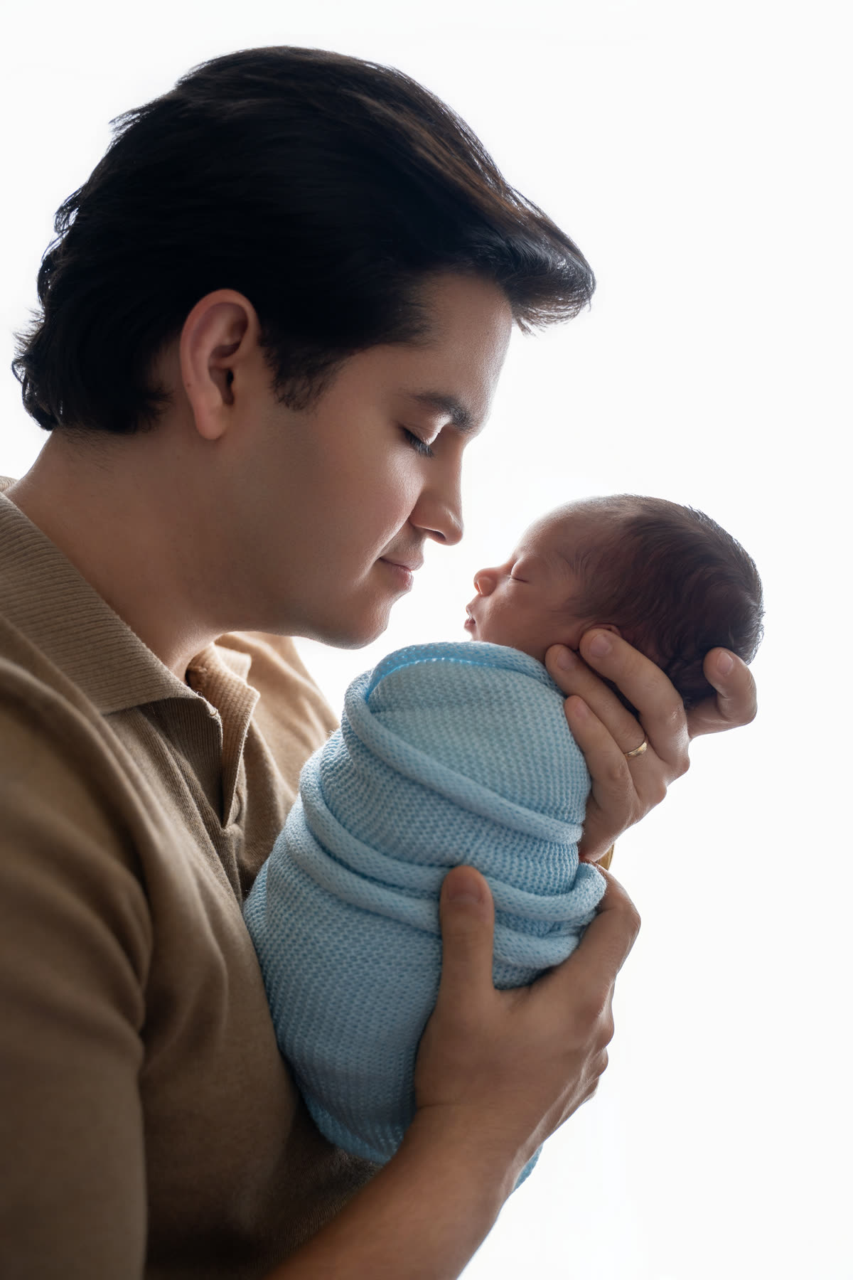 Father looking down at his newborn wrapped in blue