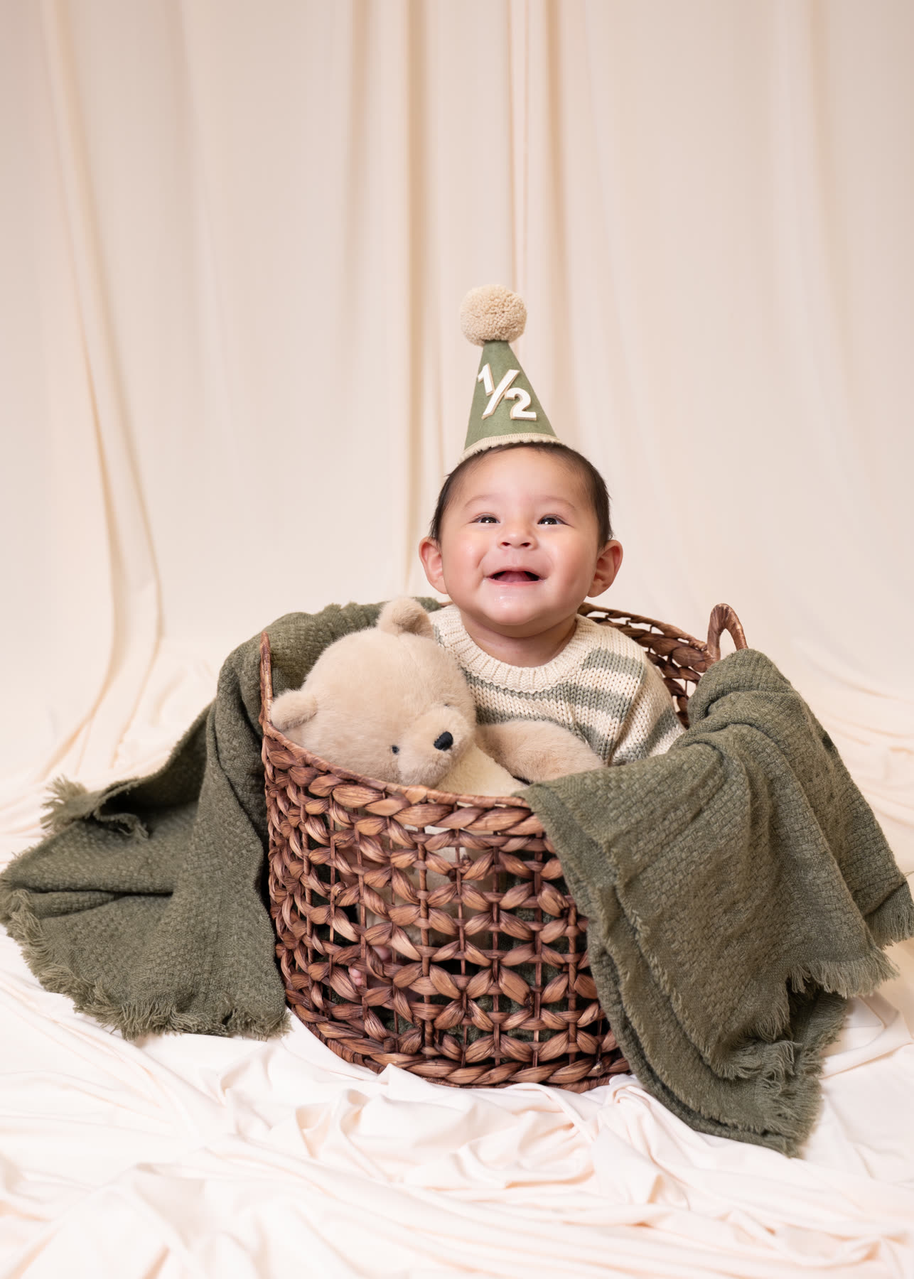 Laughing baby in a basket for a half-birthday portrait