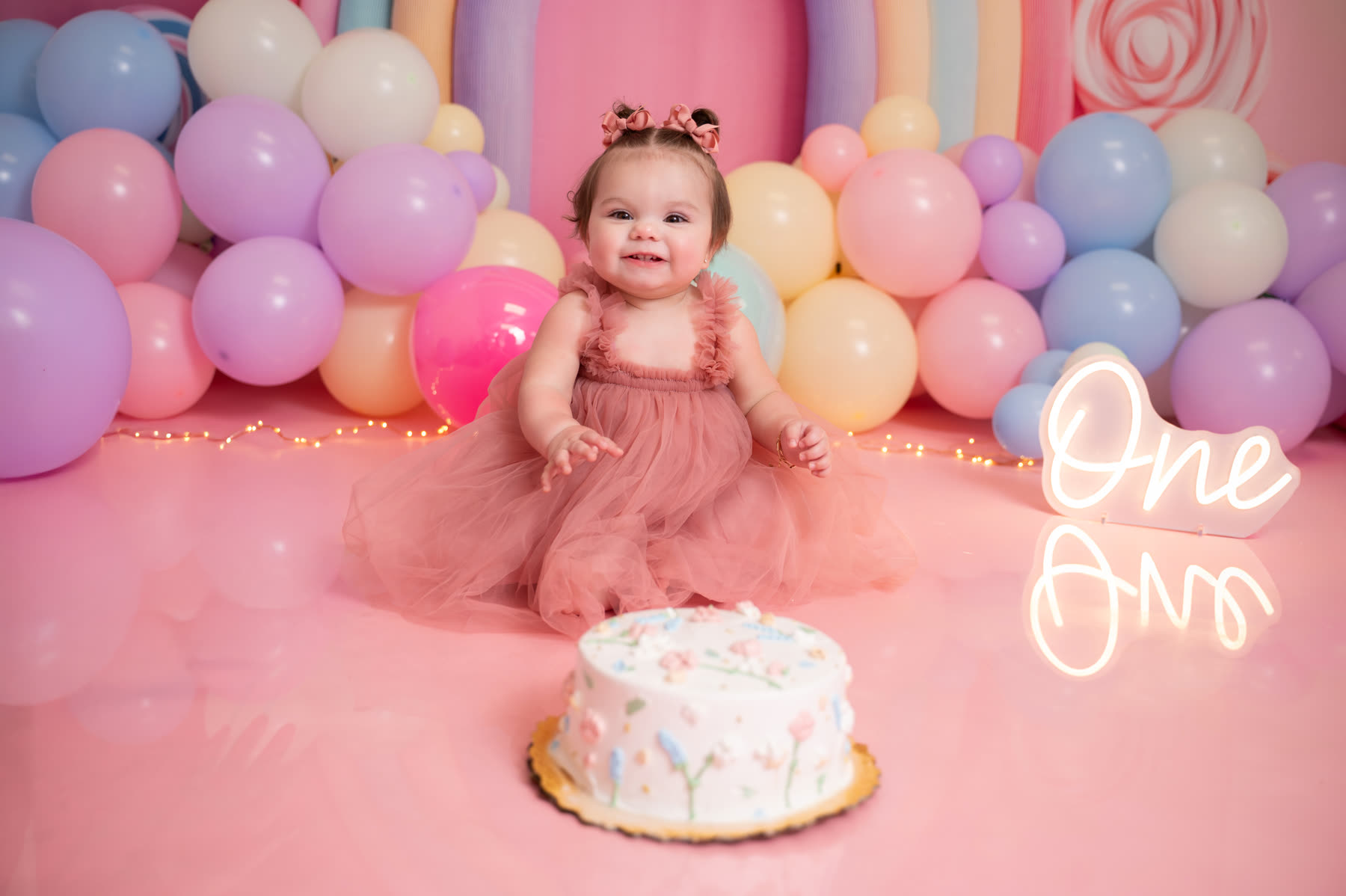 Smash cake session with pink balloons and a white cake