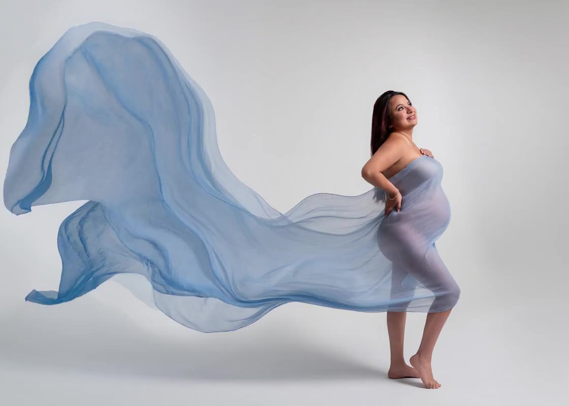 Maternity session: pale blue silk flying across a gray cyclorama