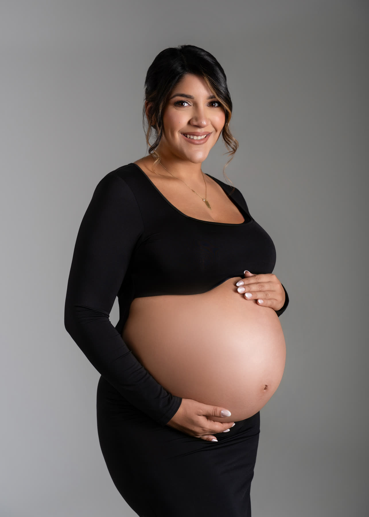 Smiling maternity portrait in black on a gray backdrop