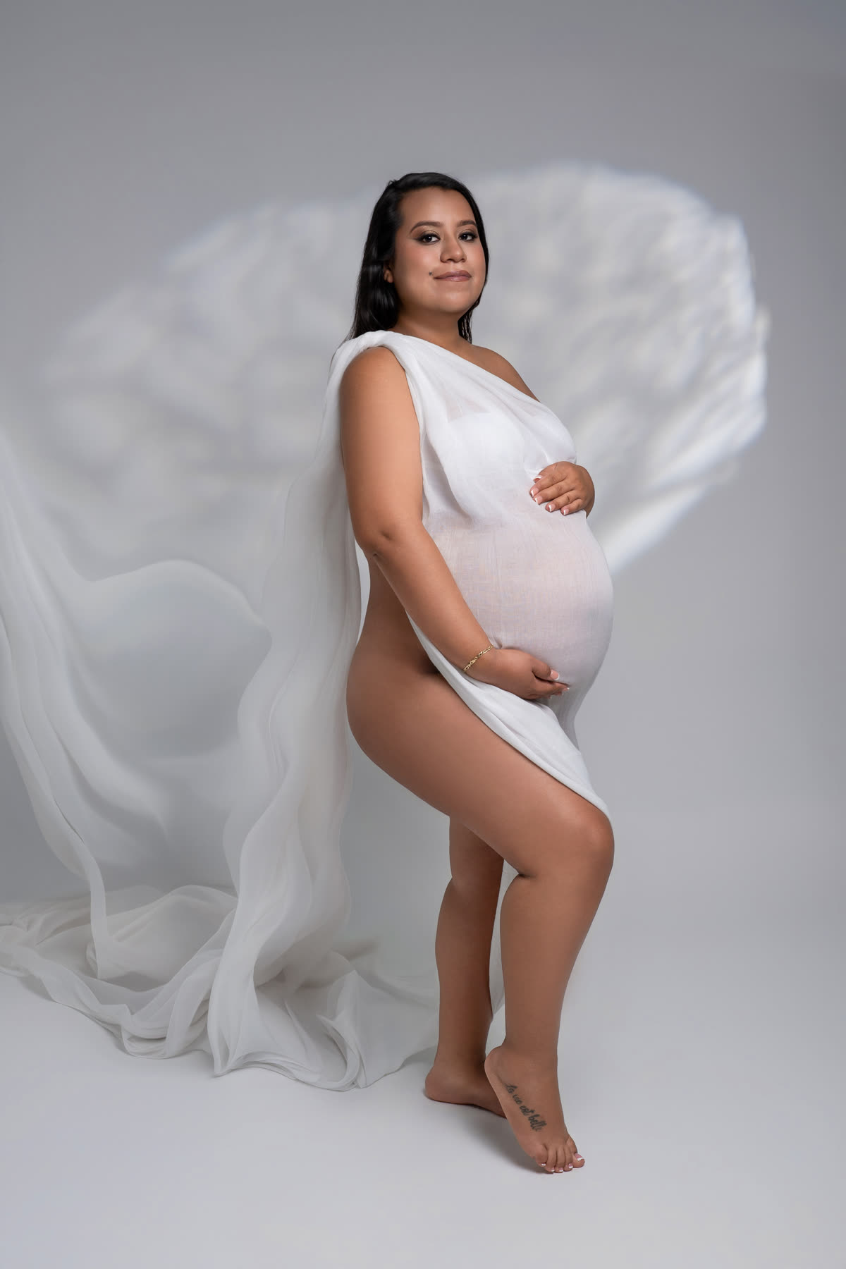 Maternity portrait wrapped in white tulle like a cloud