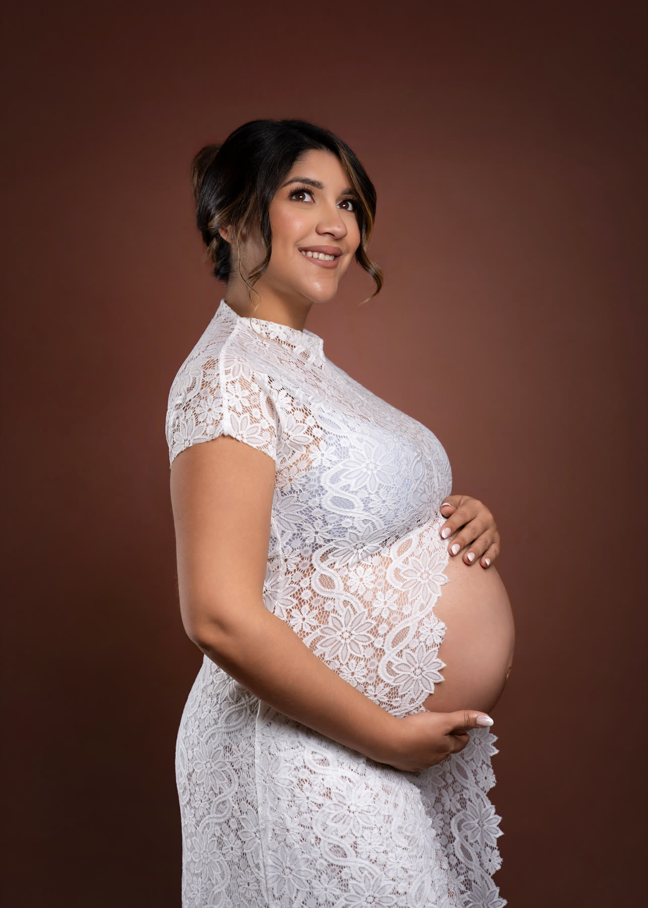 Maternity portrait in white lace on a brown backdrop
