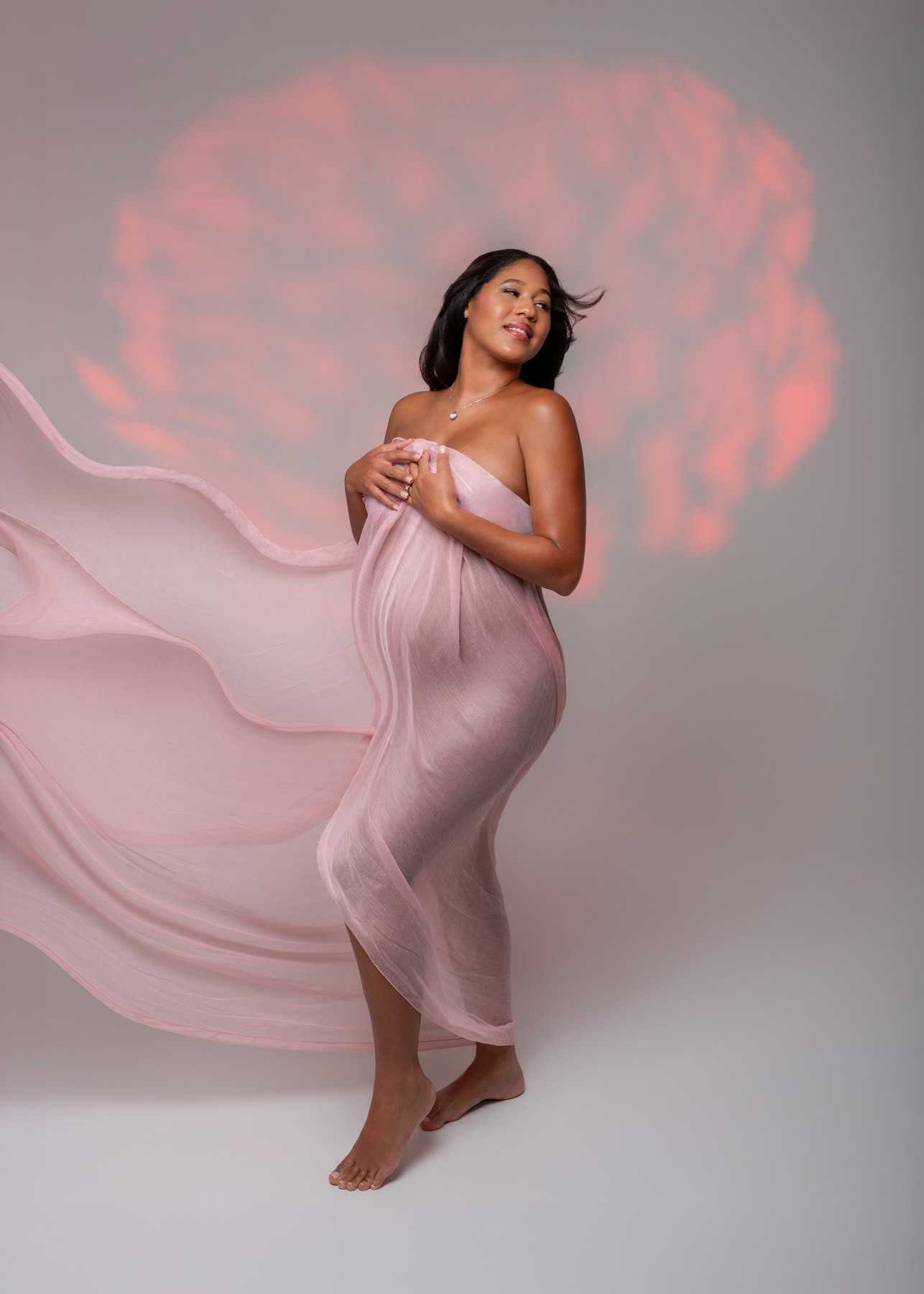 Pregnant woman wrapped in flowing pink silk