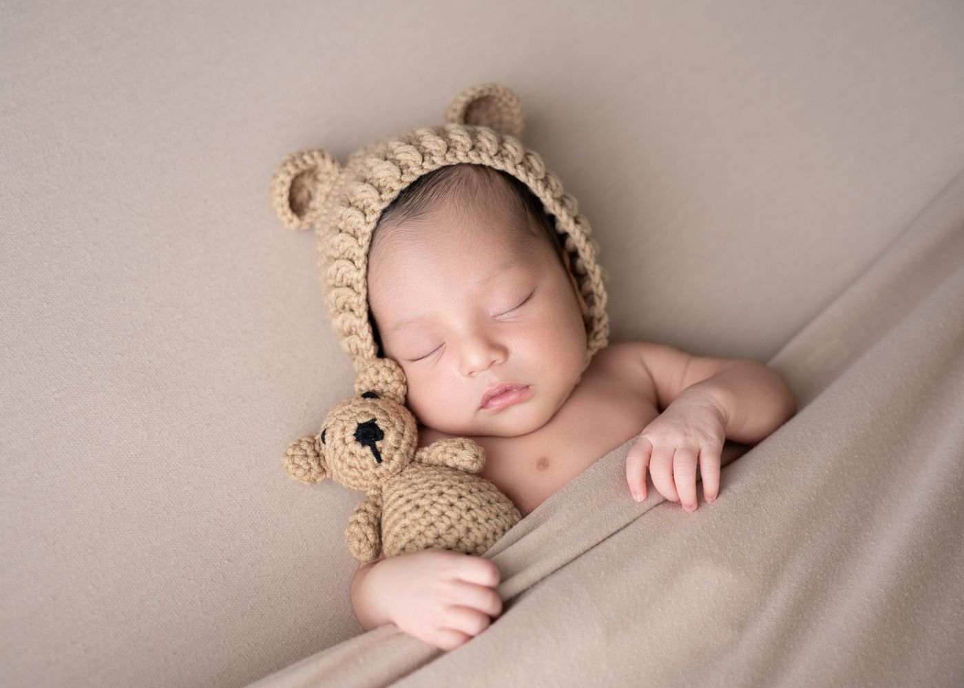 Sleeping baby in a crochet bear bonnet