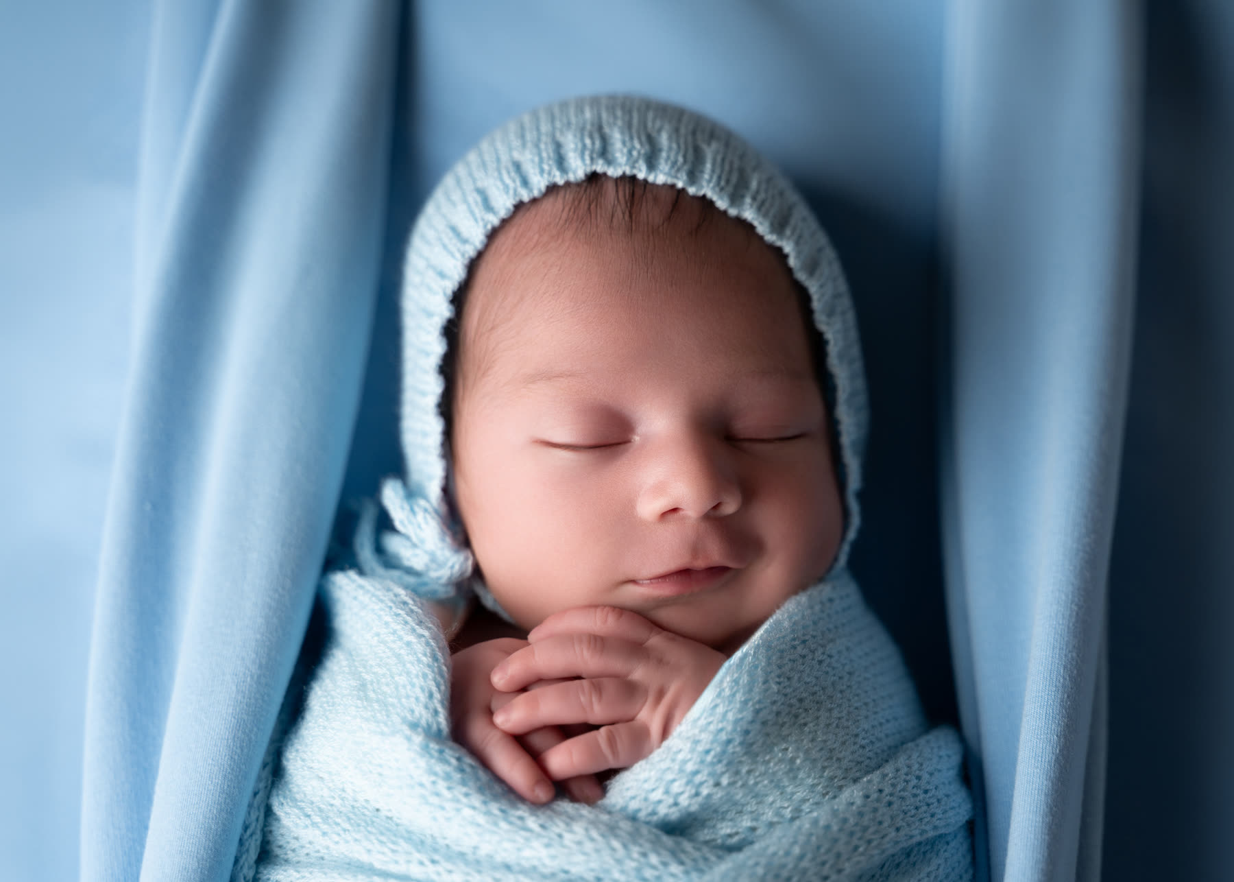 Newborn in a pale blue bonnet and wrap