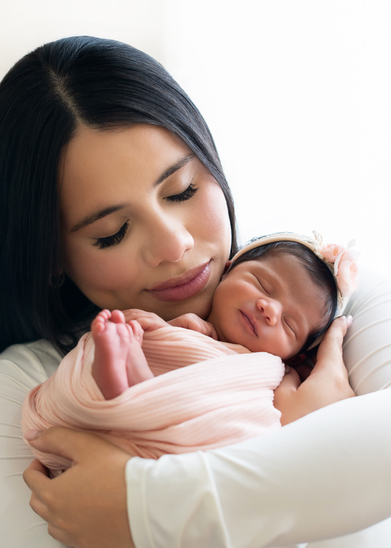 Mother holding her newborn close, eyes closed