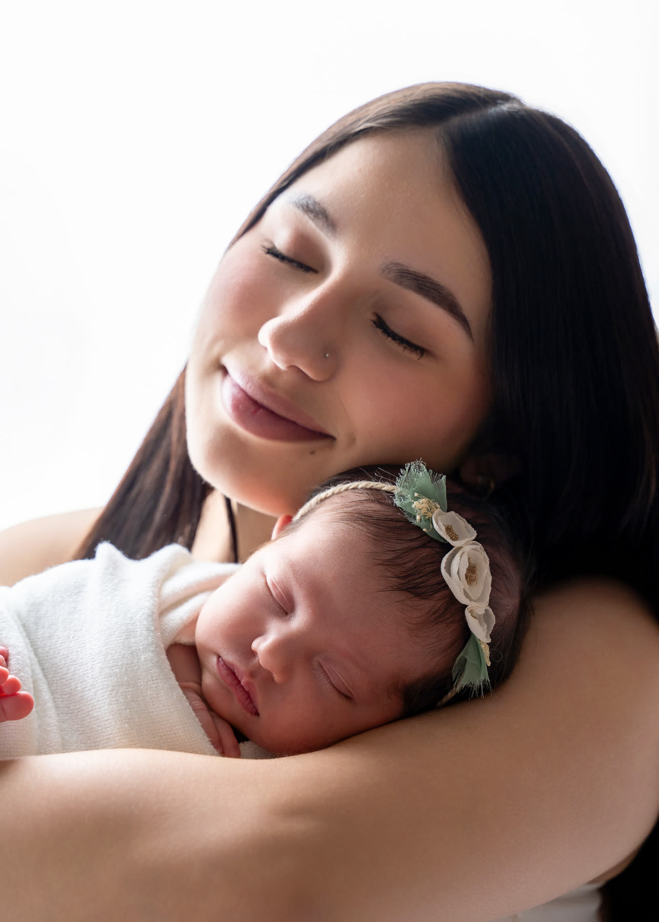 Mother cradling her sleeping newborn against her cheek